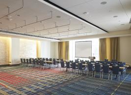 Room arranged in conference style with 6 tables facing podium 