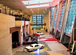 Photo overlooking lobby that has 3 cars parked parked inside with red carpet 