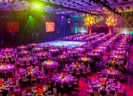 Ballroom full of fancy set tables and colorful lighting for a gala event 
