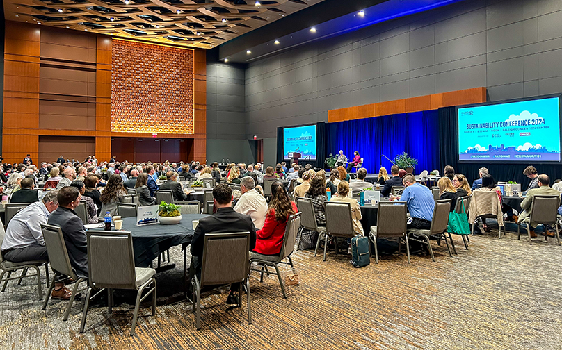 A large conference event in a ballroom with attendees listening to a sustainability panel.
