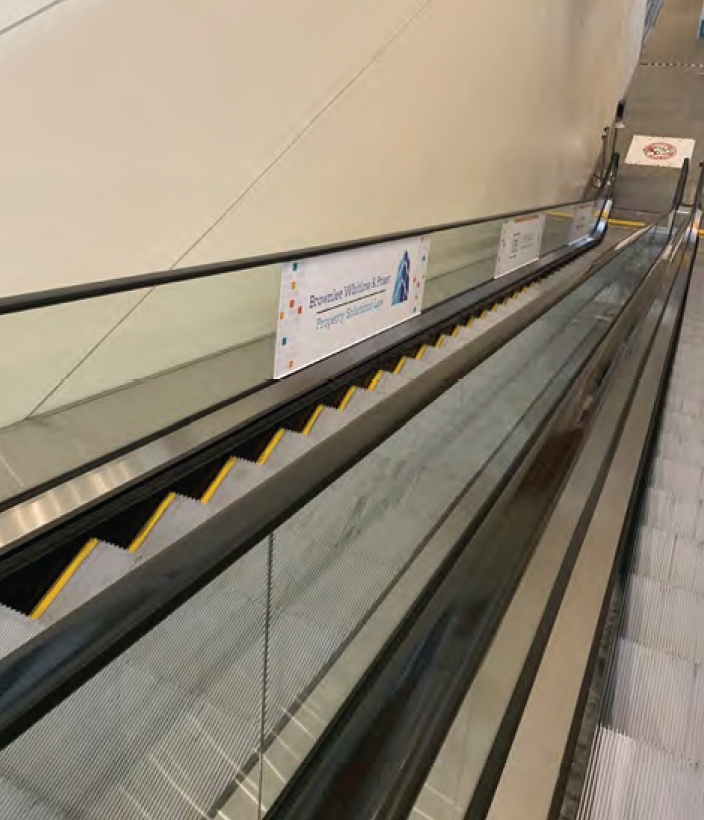 Escalator with client branding on side glass panels.