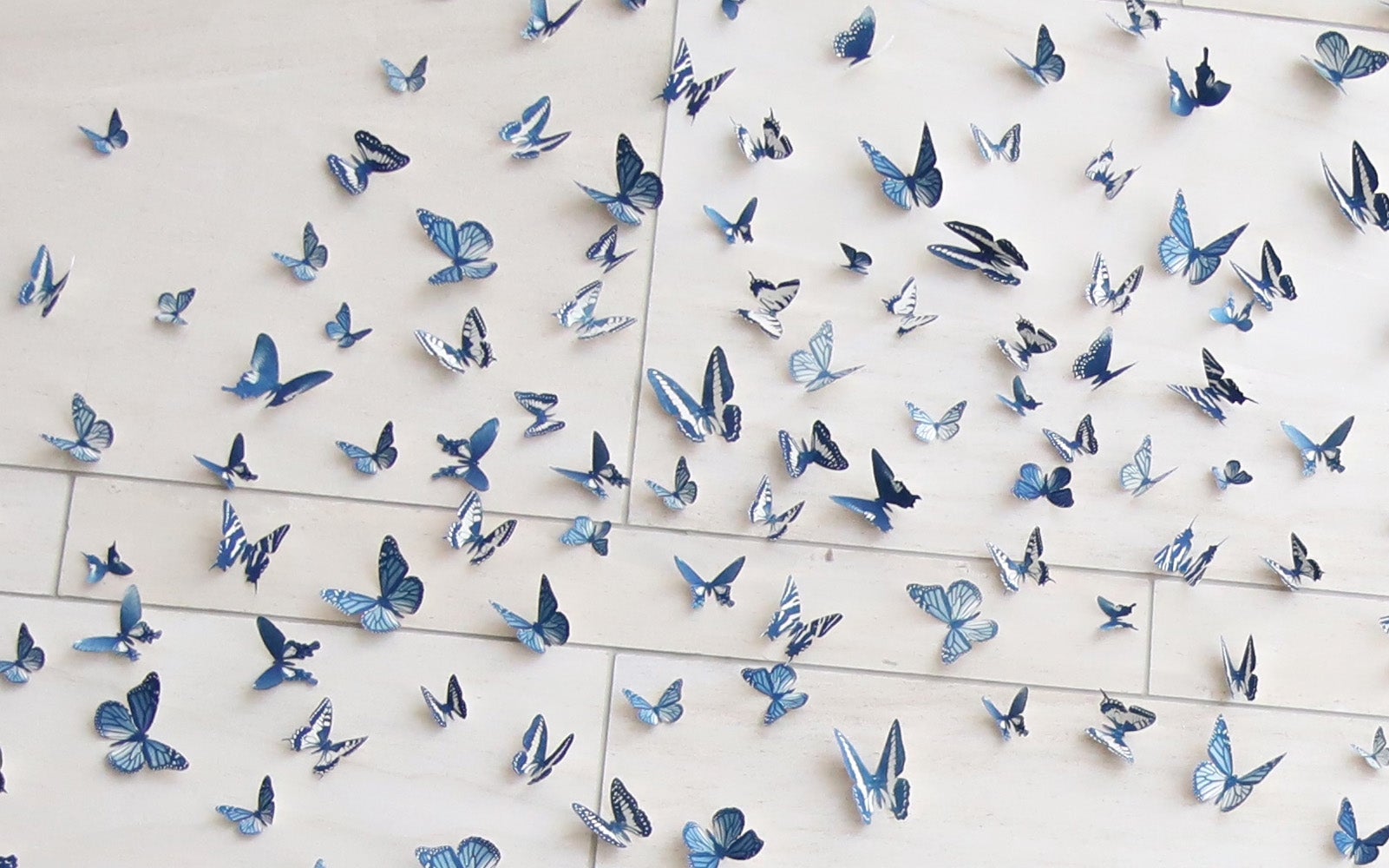 Art installation of 3-D blue butterflies in flight, creating a dynamic and elegant display on a light wall.