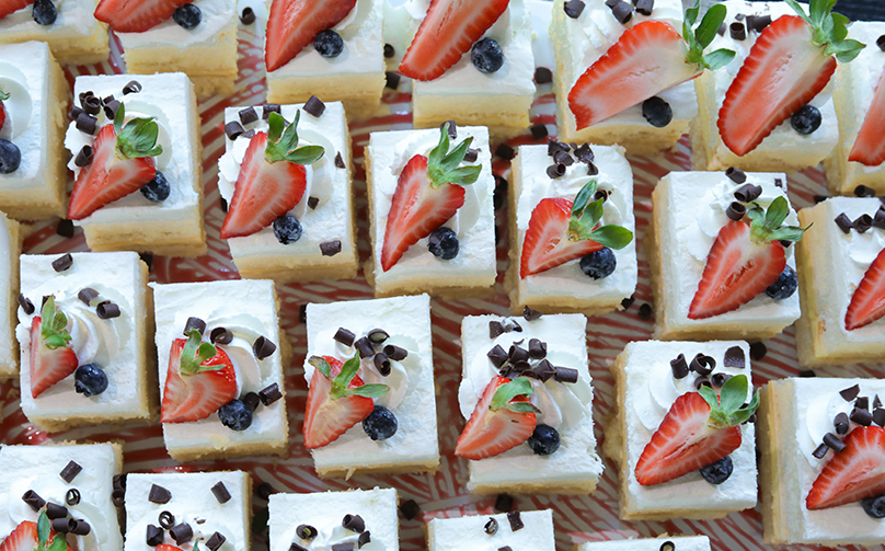Mini vanilla cakes topped with fresh strawberries, blueberries, whipped cream, and chocolate shavings.