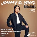 Photo of Jimmmy O Yang in white t shirt and dark blue button down in front of light brown background