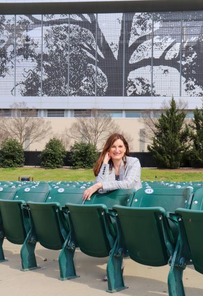 Kerry Painter sits in Red Hat Amphitheater, smiling at the camera