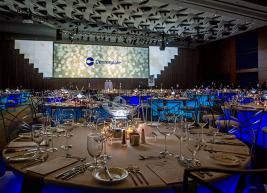 Set table inside a ballroom with wine glasses, silverware, plates 